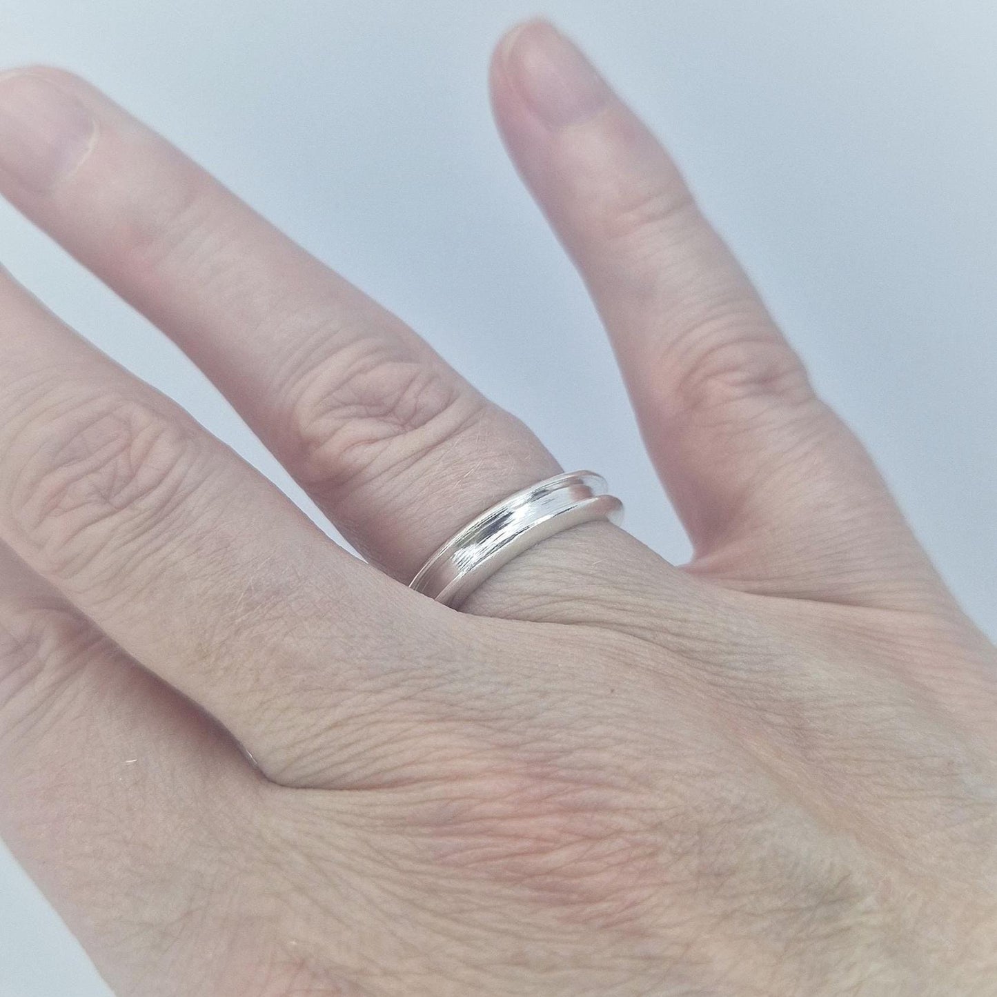 Silver channel ring worn on the finger, demonstrating the slim width, curved profile, and comfortable everyday fit.