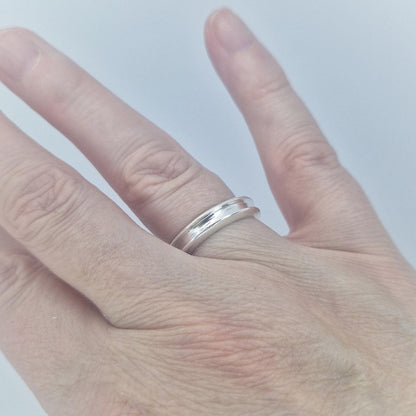 Silver channel ring worn on the finger, demonstrating the slim width, curved profile, and comfortable everyday fit.