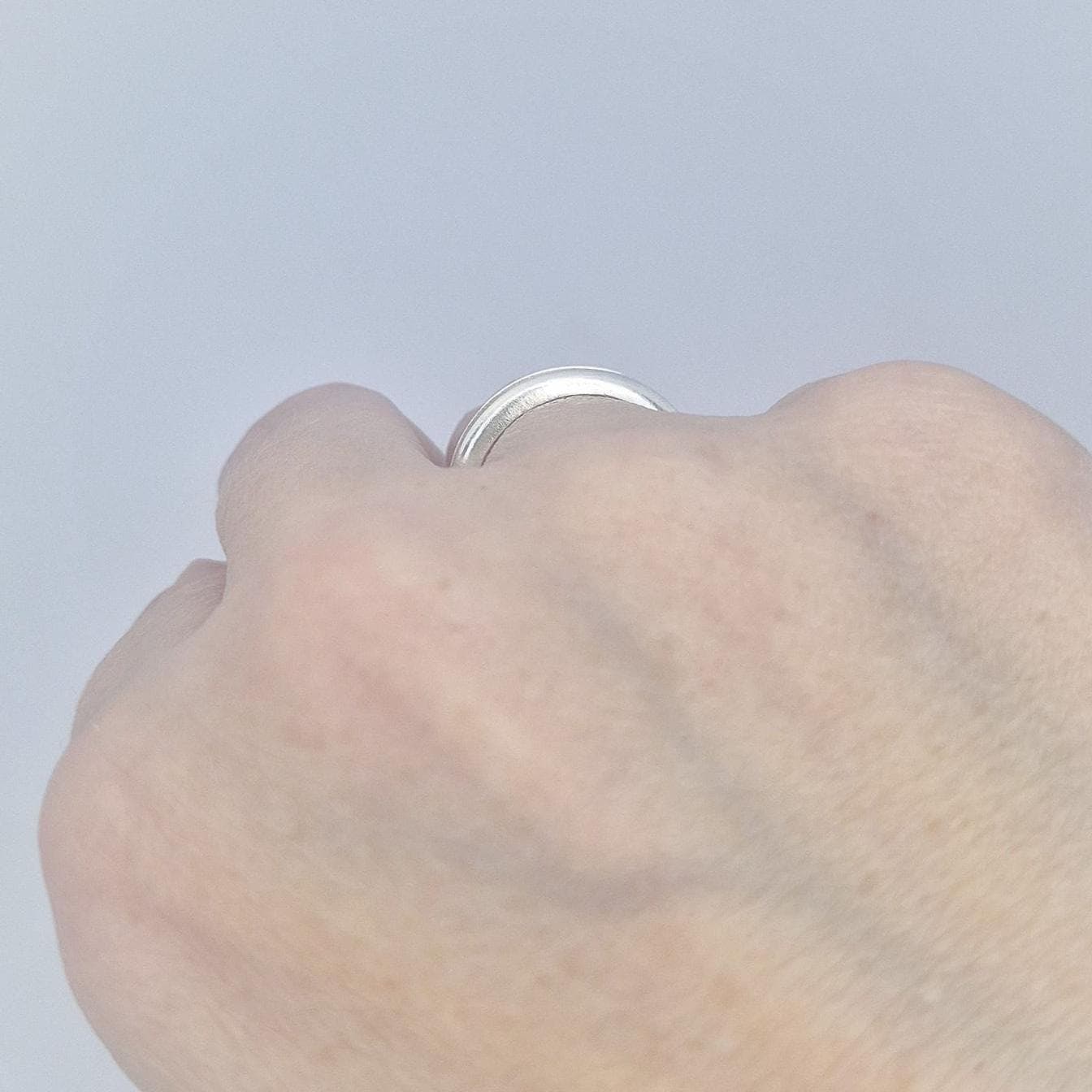 Close-up of a silver channel band worn on the hand, showing the polished surface and understated modern style.