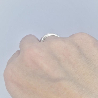 Close-up of a silver channel band worn on the hand, showing the polished surface and understated modern style.