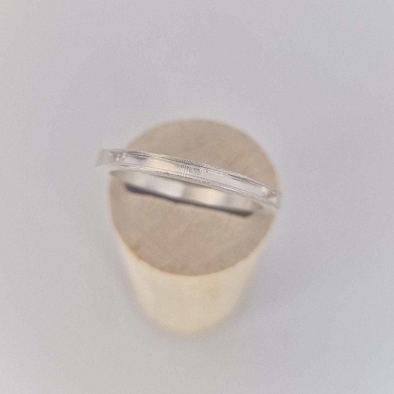 Very slim silver 120° channel ring shown in side profile on a wooden cone, highlighting the shallow channel detail and fine proportions.
