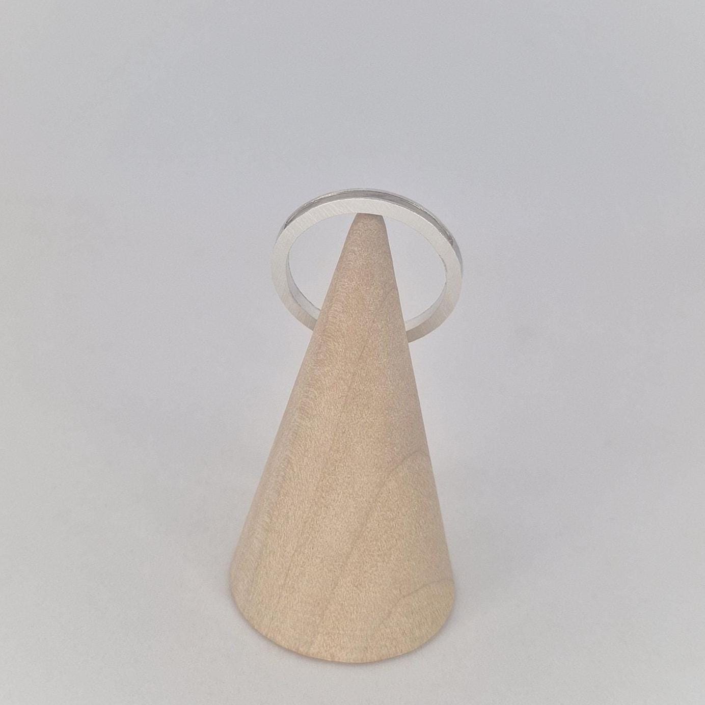Minimal silver 120° channel band viewed from above on a wooden cone, showing the clean circular form and narrow width.