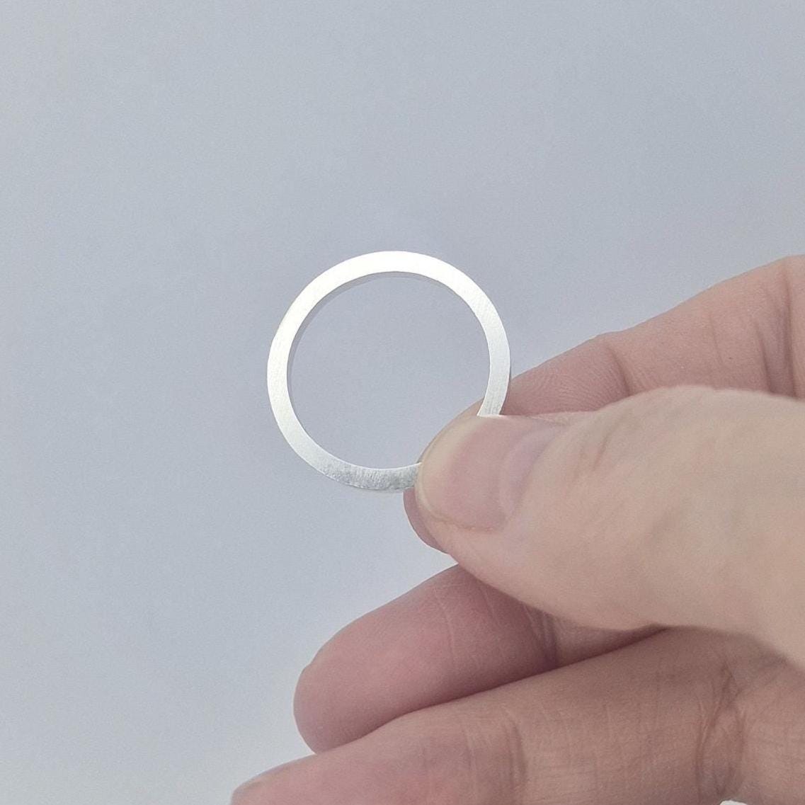 Silver 120° channel ring held flat between fingers, photographed to show the narrow band width and smooth interior.