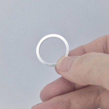 Silver 120° channel ring held flat between fingers, photographed to show the narrow band width and smooth interior.