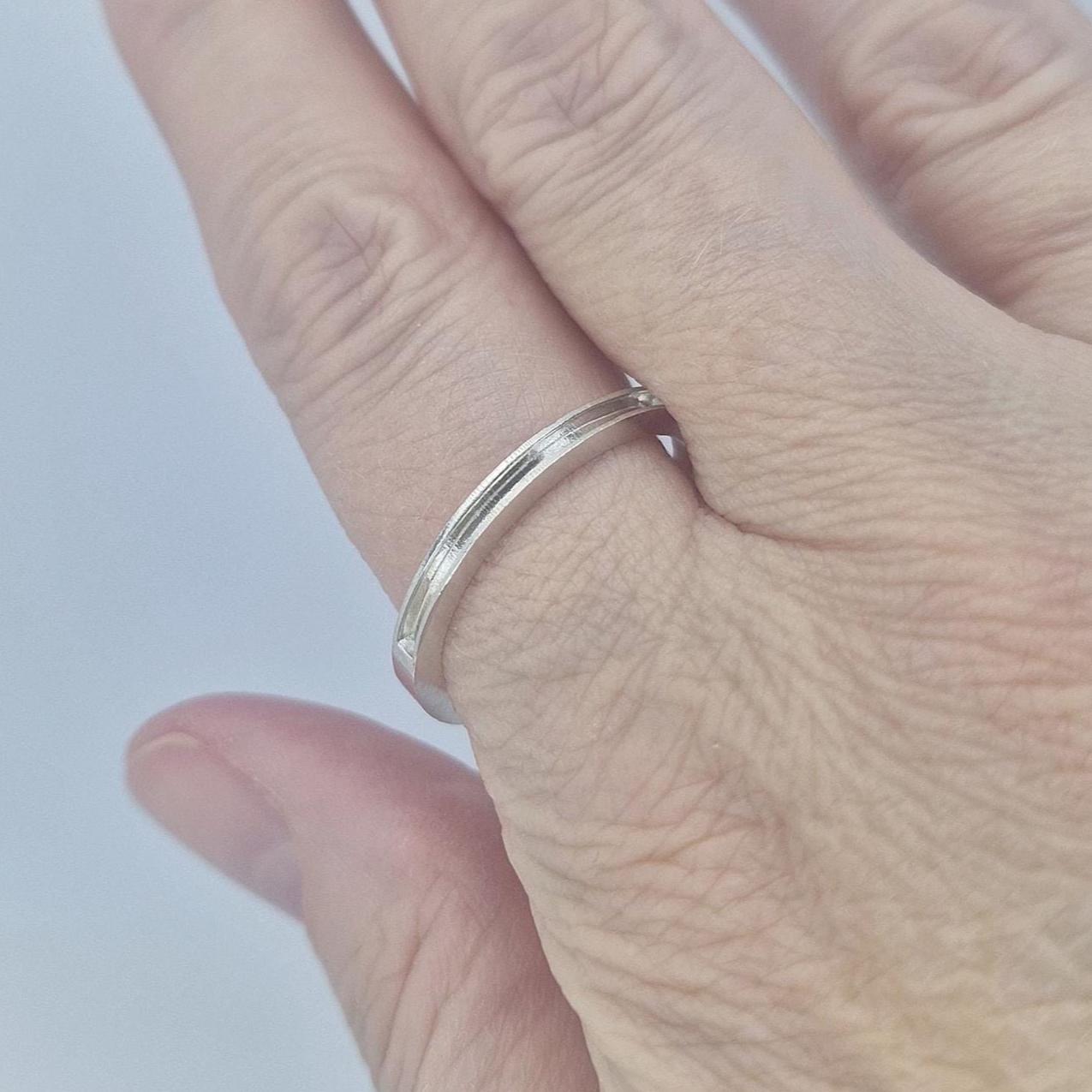 Close-up of a very slim silver 120° channel ring worn on the finger, showing the clean lines and minimalist modern style.