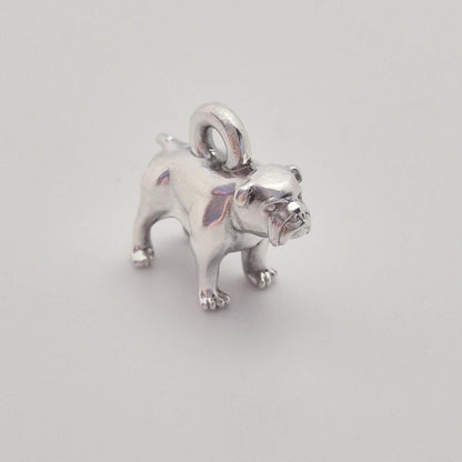 Angled front view of a silver bulldog charm on a white background, emphasising the expressive facial details and compact proportions.