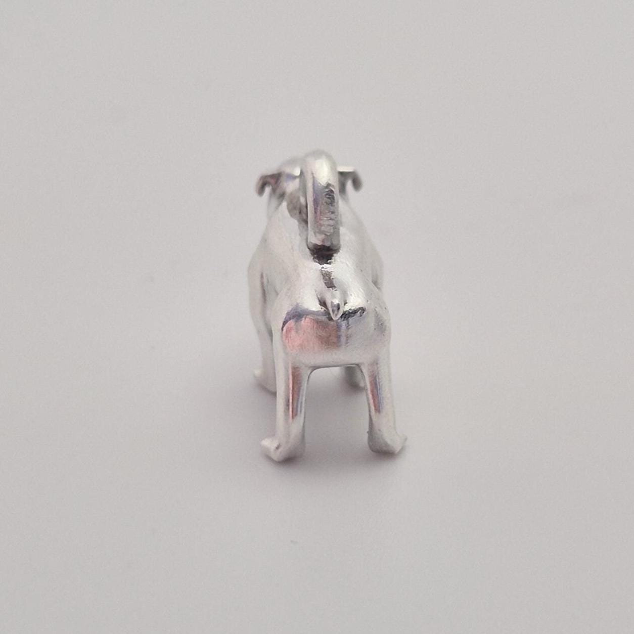 Rear view of a silver bulldog charm, highlighting the back, tail detail, and integrated hanging loop.