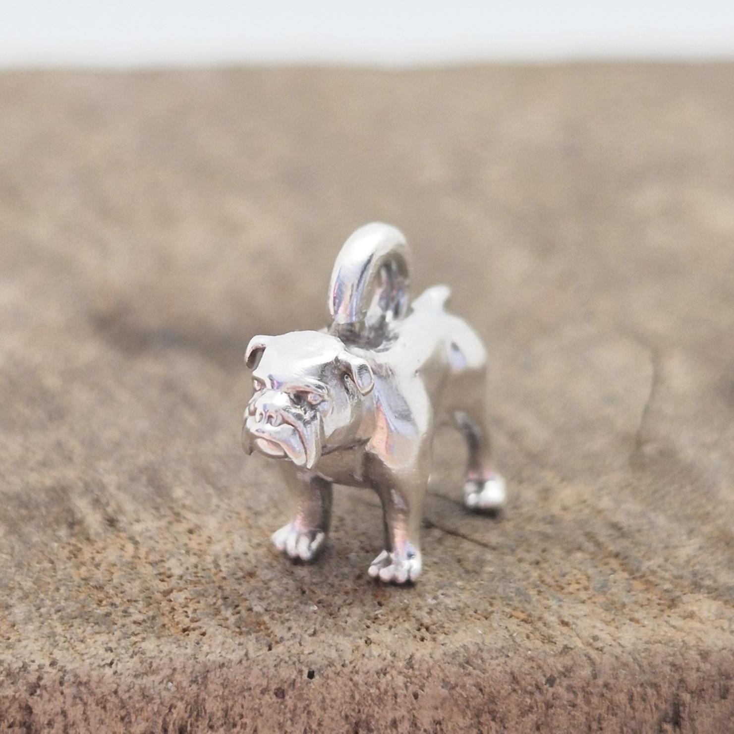 Silver bulldog charm displayed on a wooden block, photographed from the front to show scale and surface polish.