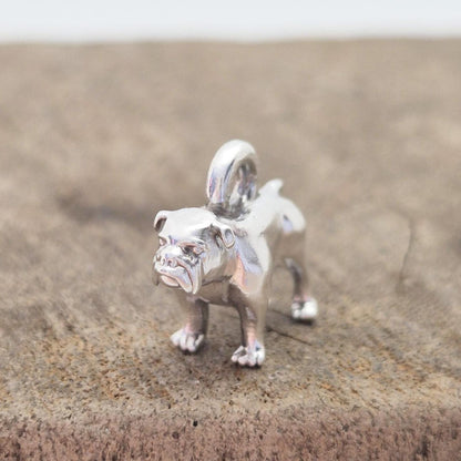 Silver bulldog charm displayed on a wooden block, photographed from the front to show scale and surface polish.