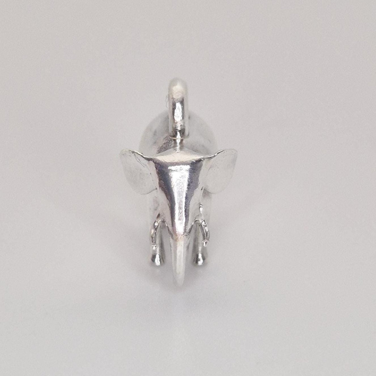 Top-down view of a polished silver elephant charm on a white background, showing the integrated hanging loop and head detail.