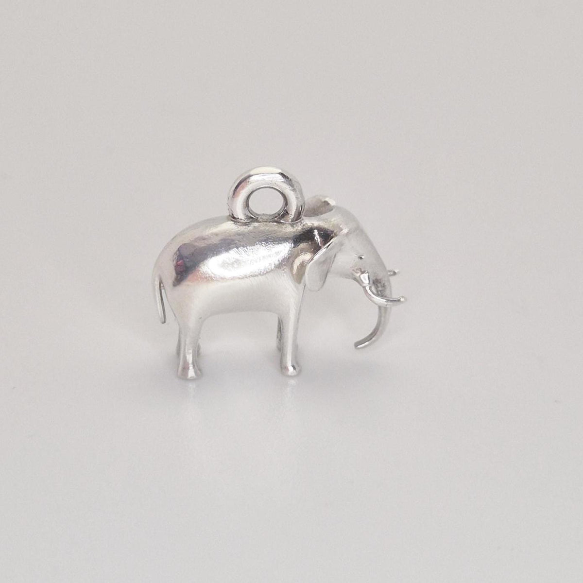 Front three-quarter view of a silver elephant charm on a white background, emphasising the trunk, ears, and solid proportions.