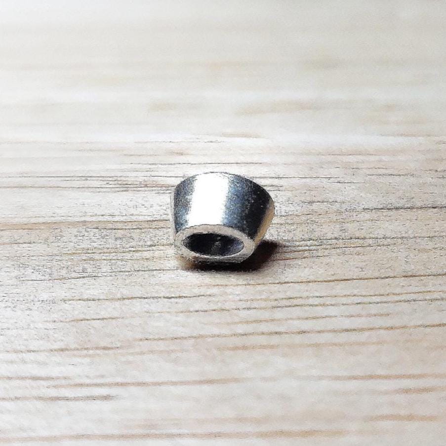 6x4mm oval sterling silver bezel setting shown from the side on a wooden surface, highlighting the tapered wall and open back.