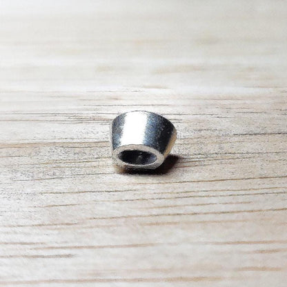 6x4mm oval sterling silver bezel setting shown from the side on a wooden surface, highlighting the tapered wall and open back.
