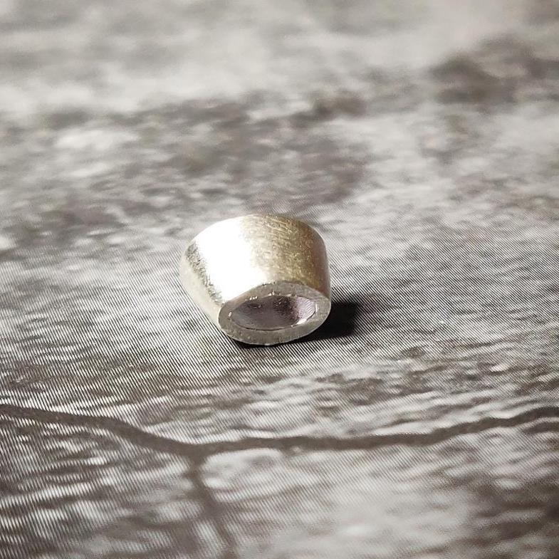 6x4mm oval silver bezel viewed from the front on a dark stone-like background, showing the polished rim and open back.