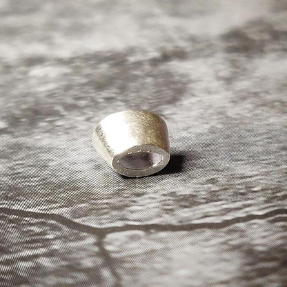 6x4mm oval silver bezel viewed from the front on a dark stone-like background, showing the polished rim and open back.