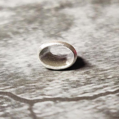 Upright 6x4mm oval silver bezel setting on a dark surface, showing the clean rim and inner seat for an oval stone.