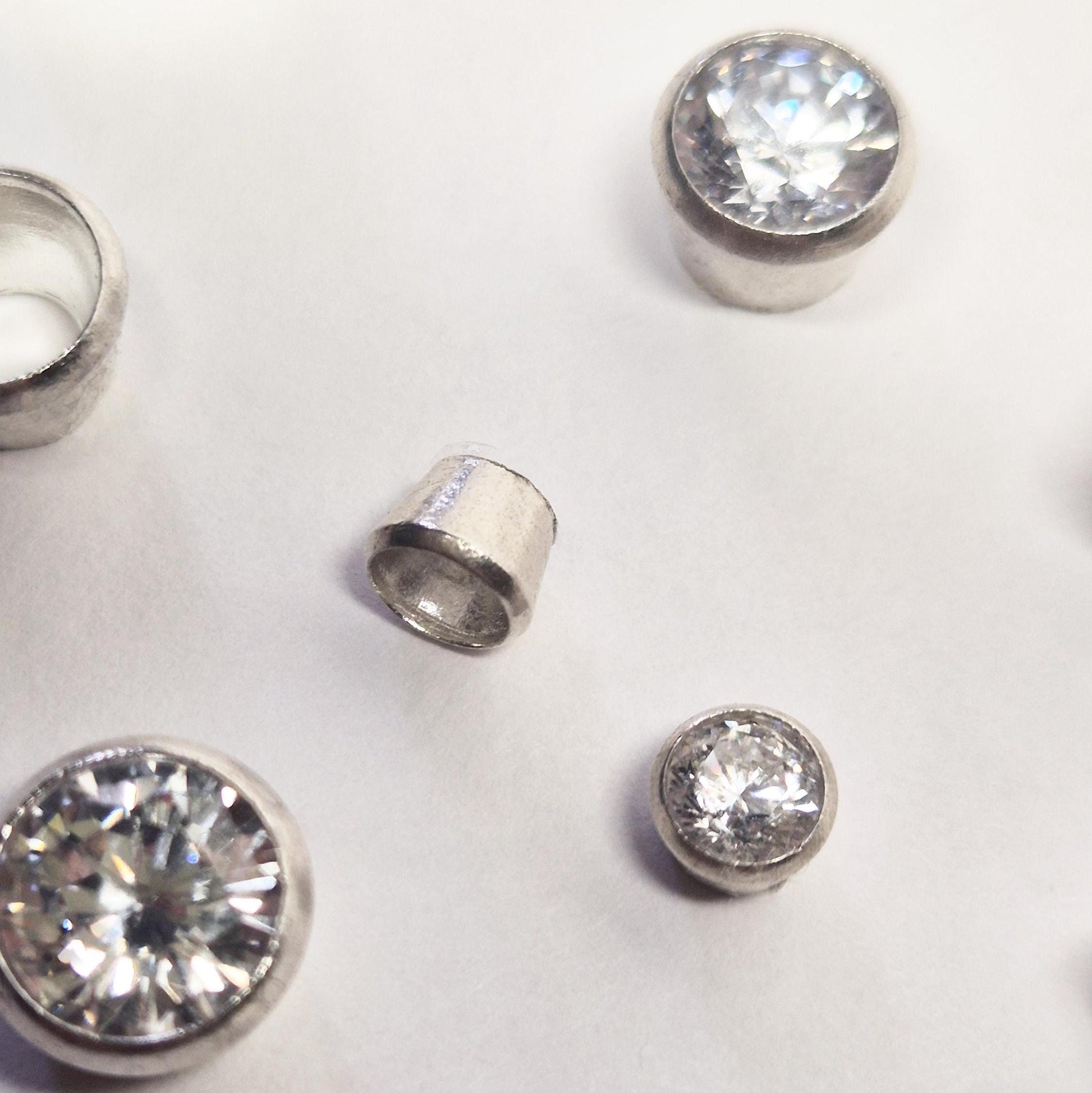 Close up of a 4mm round bezel on a white background, surrounded by a group of bezels.