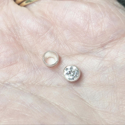 Sterling silver round bezel cup and matching gemstone shown in hand for scale, jewellery bezel setting component.
