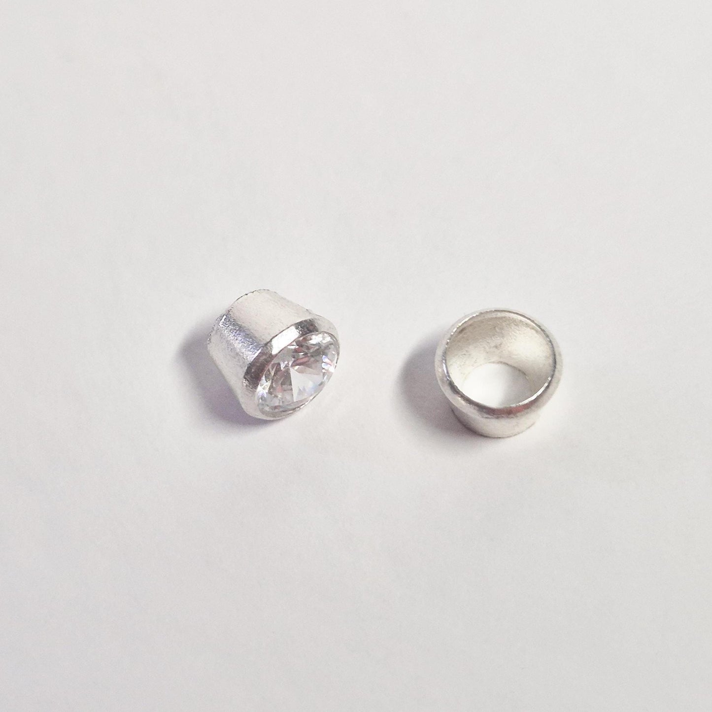 Side view comparison of gemstone set in sterling silver bezel and empty bezel cup for jewellery making.