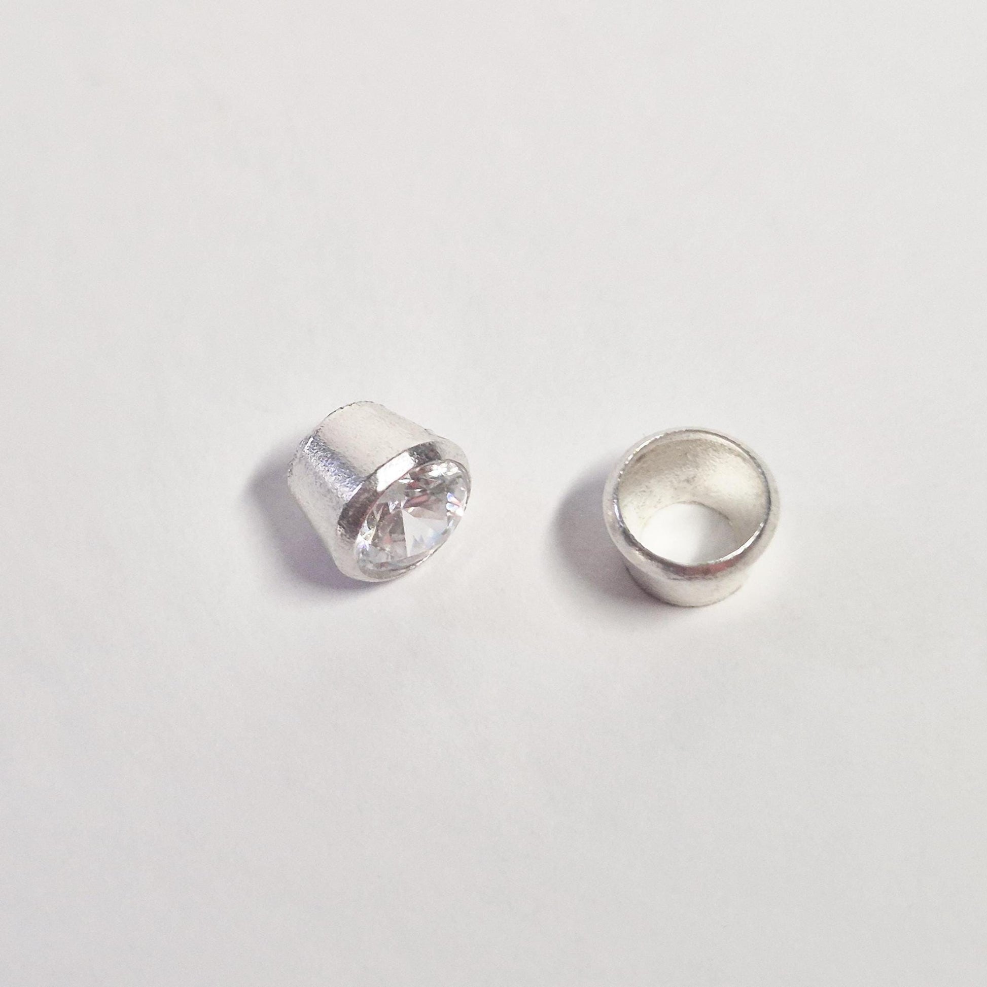 Side view comparison of gemstone set in sterling silver bezel and empty bezel cup for jewellery making.