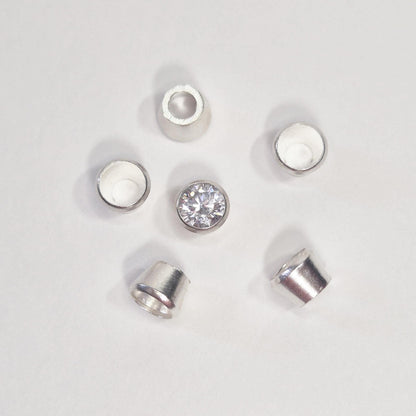 Arrangement of sterling silver bezel cups surrounding a round gemstone, showing tapered bezel settings for jewellery making.