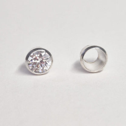 Finished example of round gemstone set in sterling silver bezel next to empty bezel cup, demonstrating jewellery setting component.