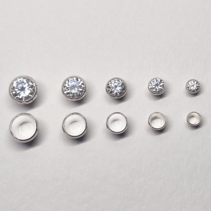 Row of sterling silver bezel cups and matching round stones in multiple sizes, showing graduated bezel settings for jewellery making.