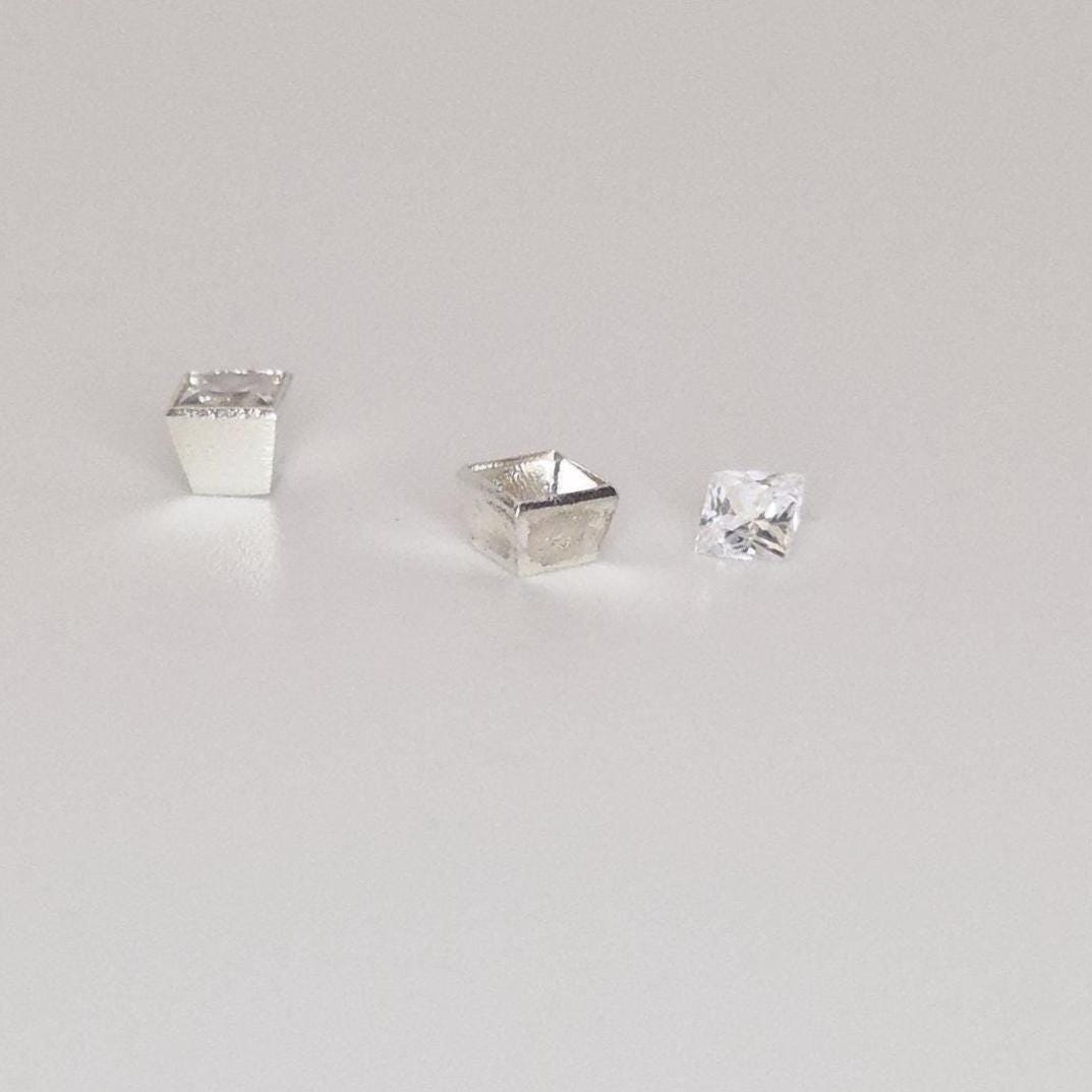 Square bezel setting in sterling silver shown with loose princess-cut gemstone on white background