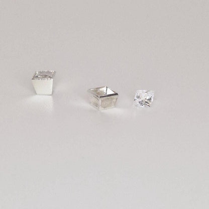 Square bezel setting in sterling silver shown with loose princess-cut gemstone on white background