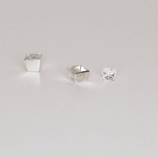 Square bezel setting in sterling silver shown with loose princess-cut gemstone on white background