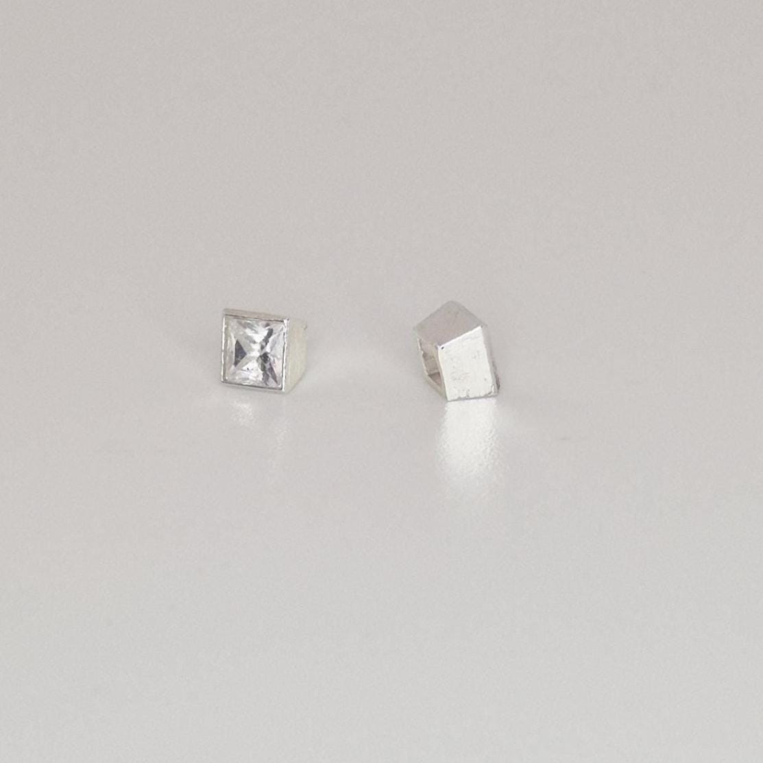 Finished square bezel setting with princess-cut stone next to empty setting and loose gemstone