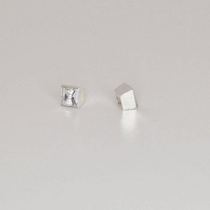 Finished square bezel setting with princess-cut stone next to empty setting and loose gemstone