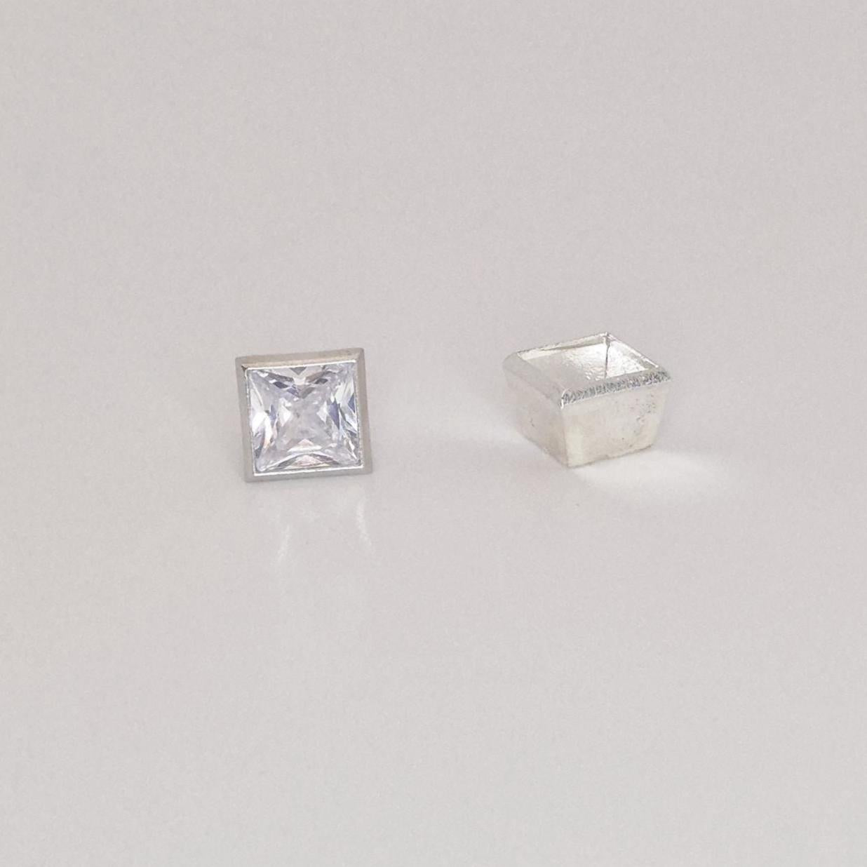 Princess cut square gemstone next to unfinished sterling silver bezel setting viewed from an angle.