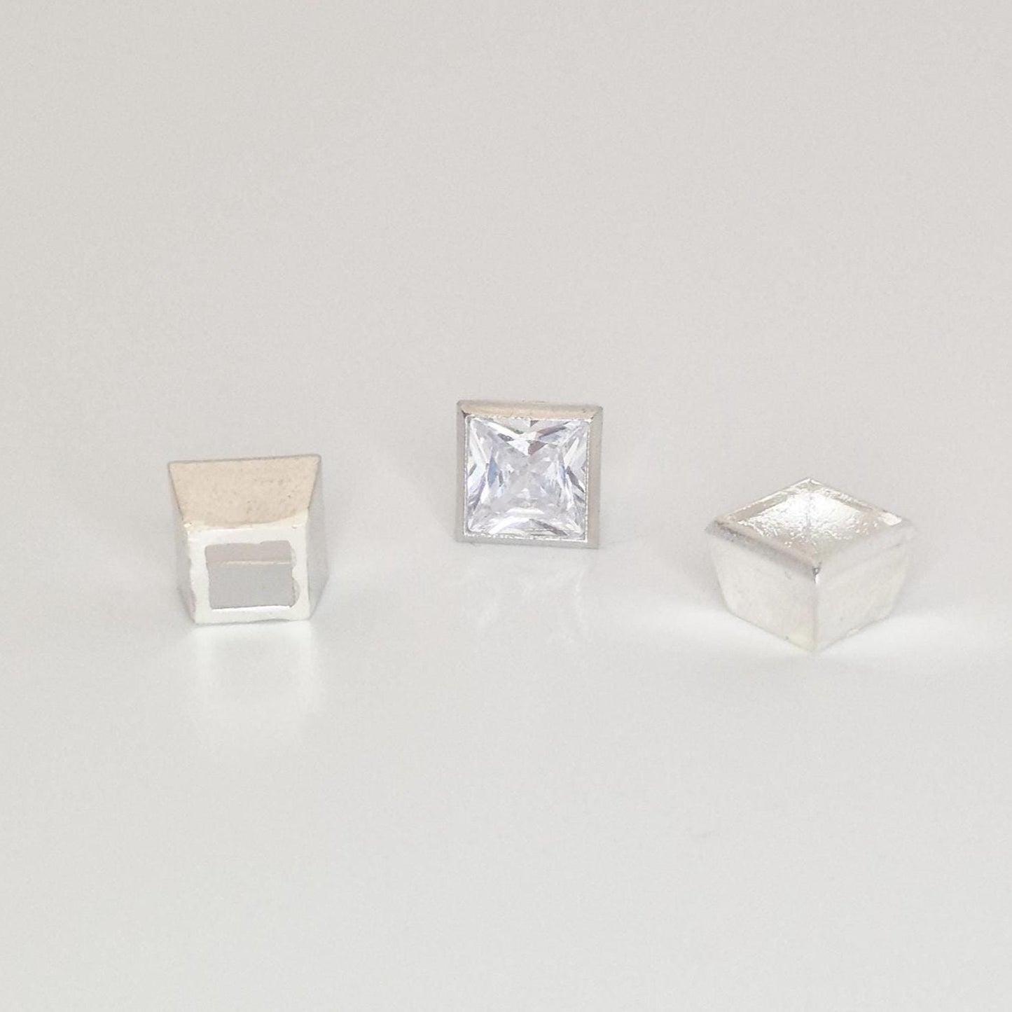Textured sterling silver square bezel setting components with a princess cut gemstone on a white background.