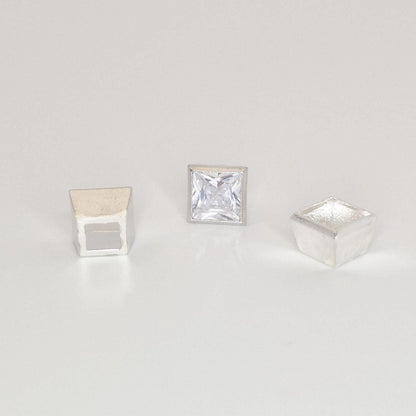 Textured sterling silver square bezel setting components with a princess cut gemstone on a white background.
