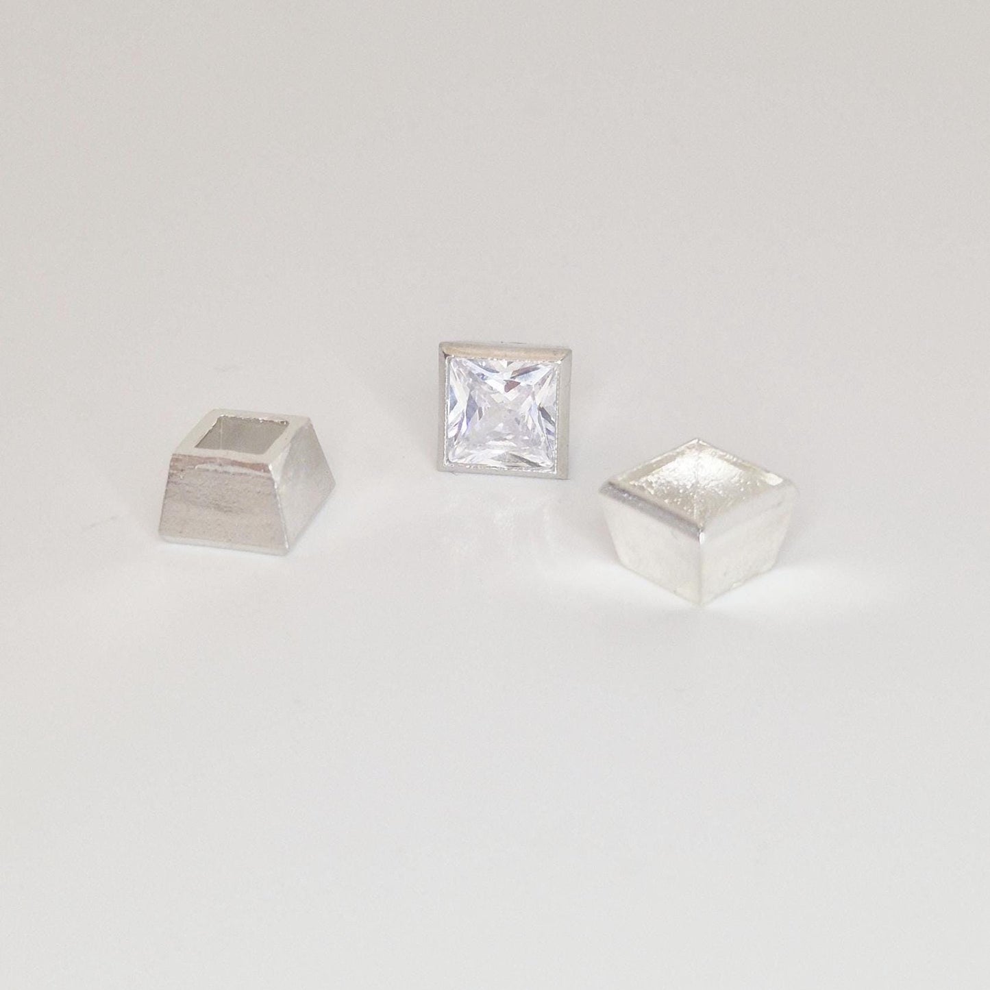 Princess cut square gemstone centred between two unfinished sterling silver bezel setting cups.