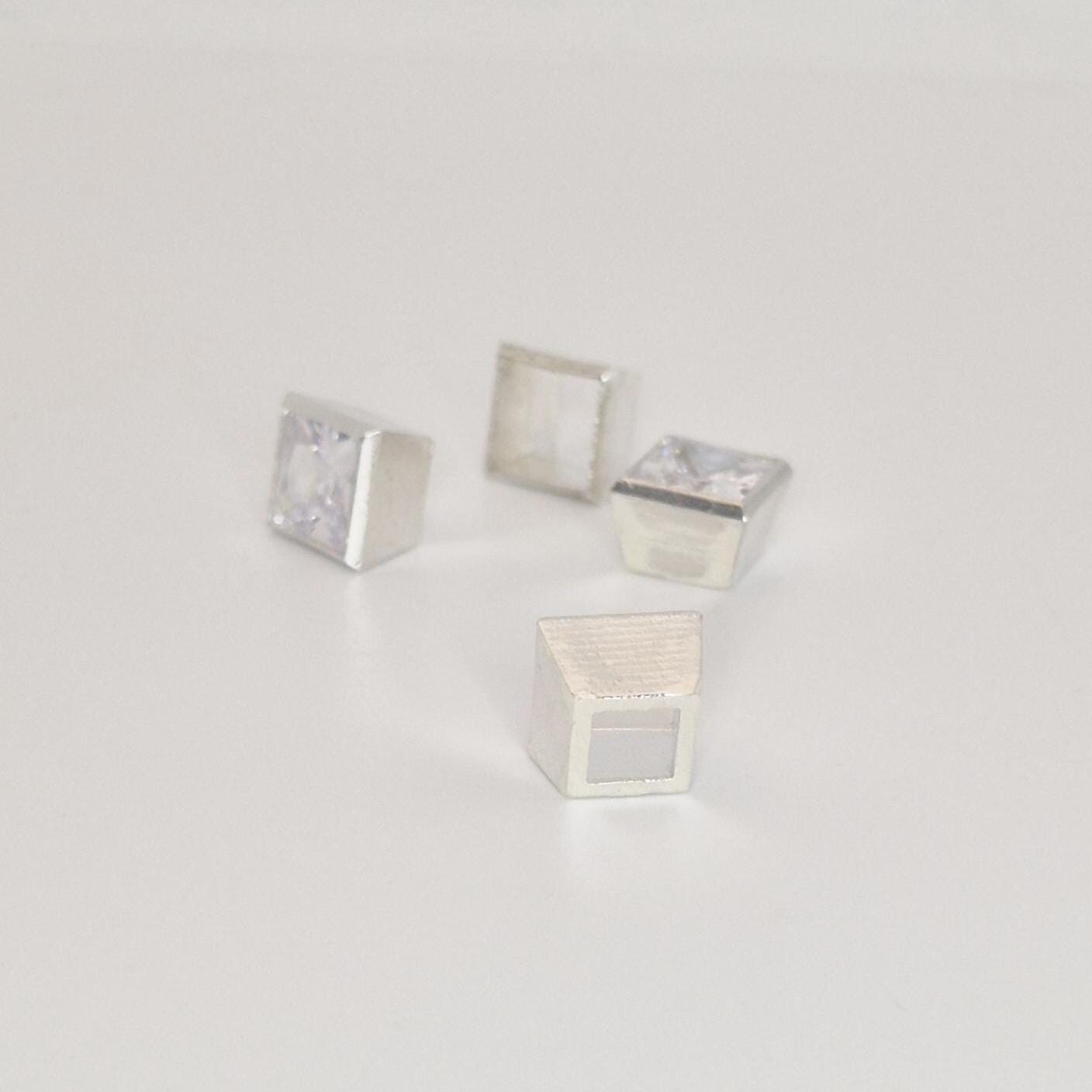 Multiple 7mm square bezel setting components in sterling silver arranged with princess cut gemstone.