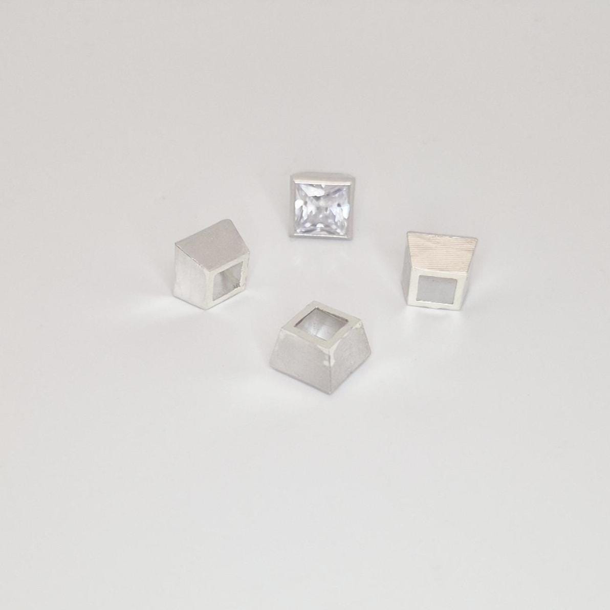 Group of 8mm square bezel settings in sterling silver with one princess cut stone mounted.