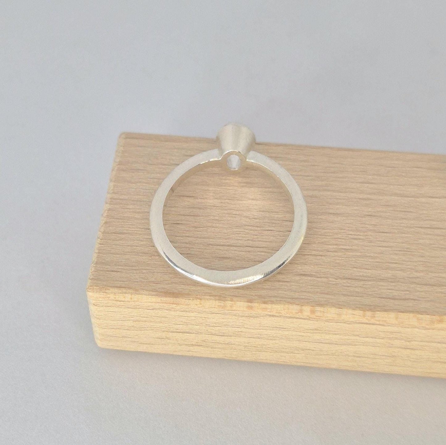 A silver 6x4mm Oval Bezel Ring viewed from the bottom angle to see the base of the gem setting.