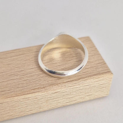 Minimalist sterling silver round signet ring blank on wooden display block, polished tapered band