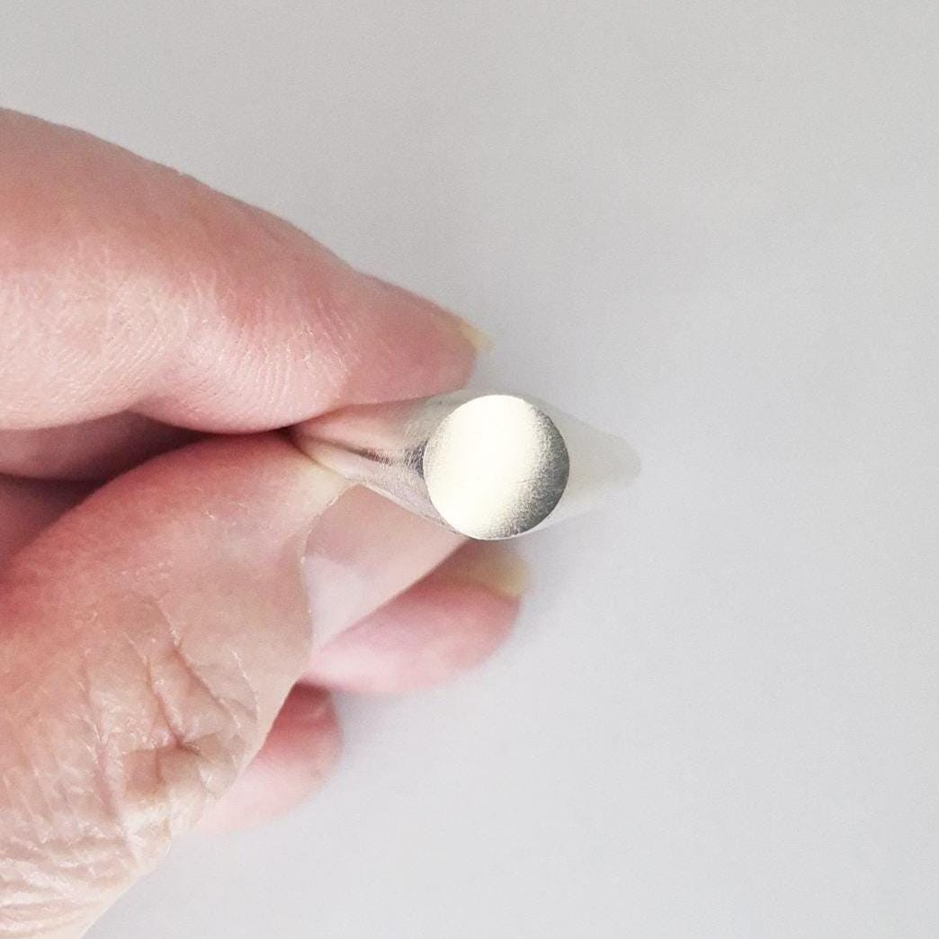 Close-up of round signet ring face, flat circular top ready for engraving, satin finish silver