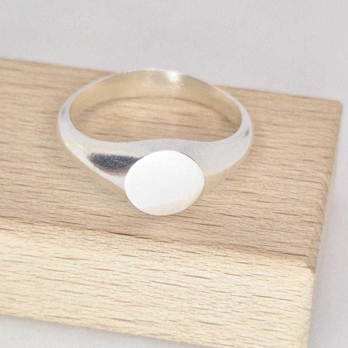 Sterling silver signet ring angled perspective, round blank face for engraving, modern minimalist design