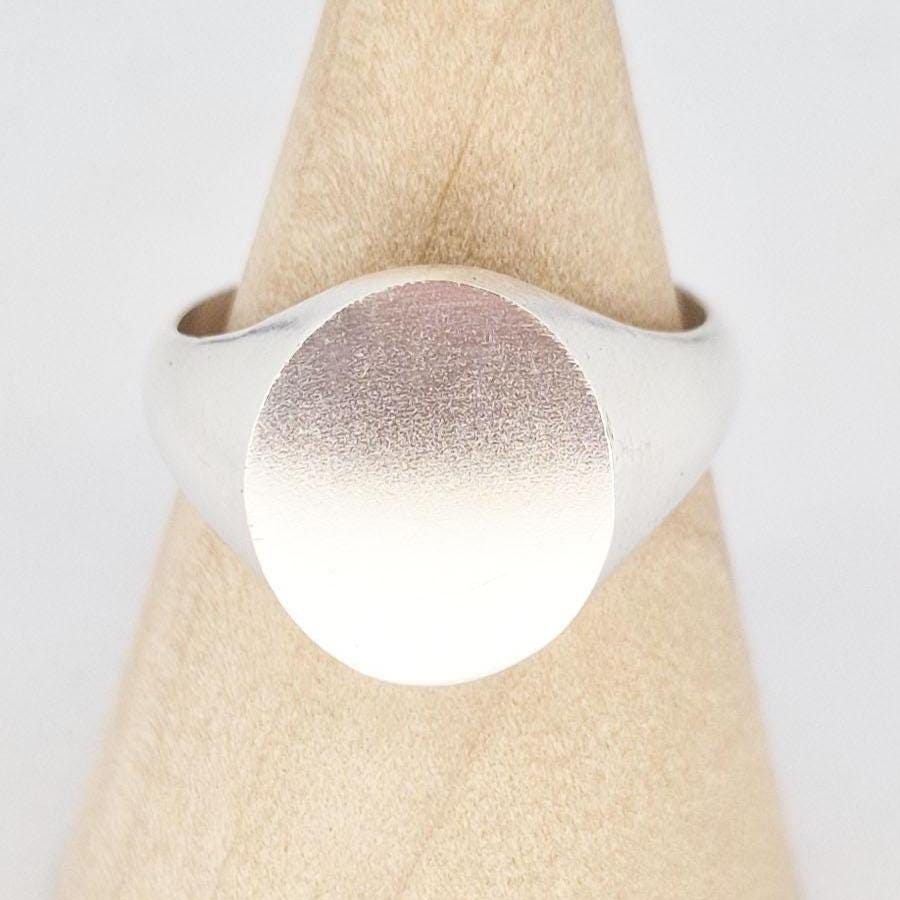 Macro close-up of oval signet ring face showing fine satin texture and smooth edges