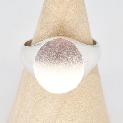 Macro close-up of oval signet ring face showing fine satin texture and smooth edges