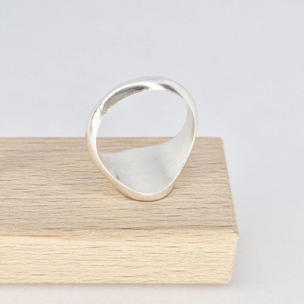 Interior view of oval signet ring band in silver displayed on wooden block