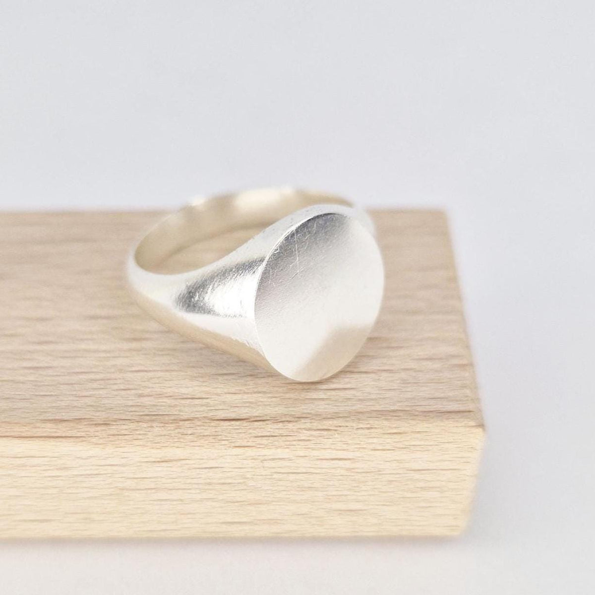 Side profile of oval silver signet ring showing tapered shank and satin-polished finish