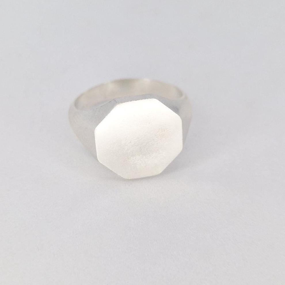 Front view of octagon silver signet ring on white background with flat brushed face