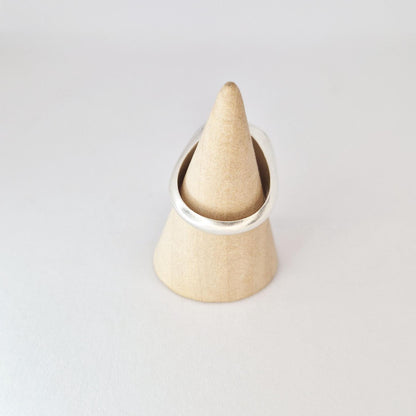 Round signet ring displayed on wooden cone stand, featuring large flat 18mm face with brushed silver finish.