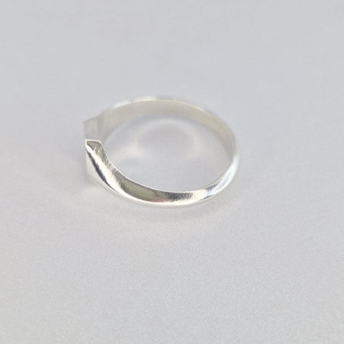 Side view of minimalist silver signet ring with hexagon top and smooth curved band