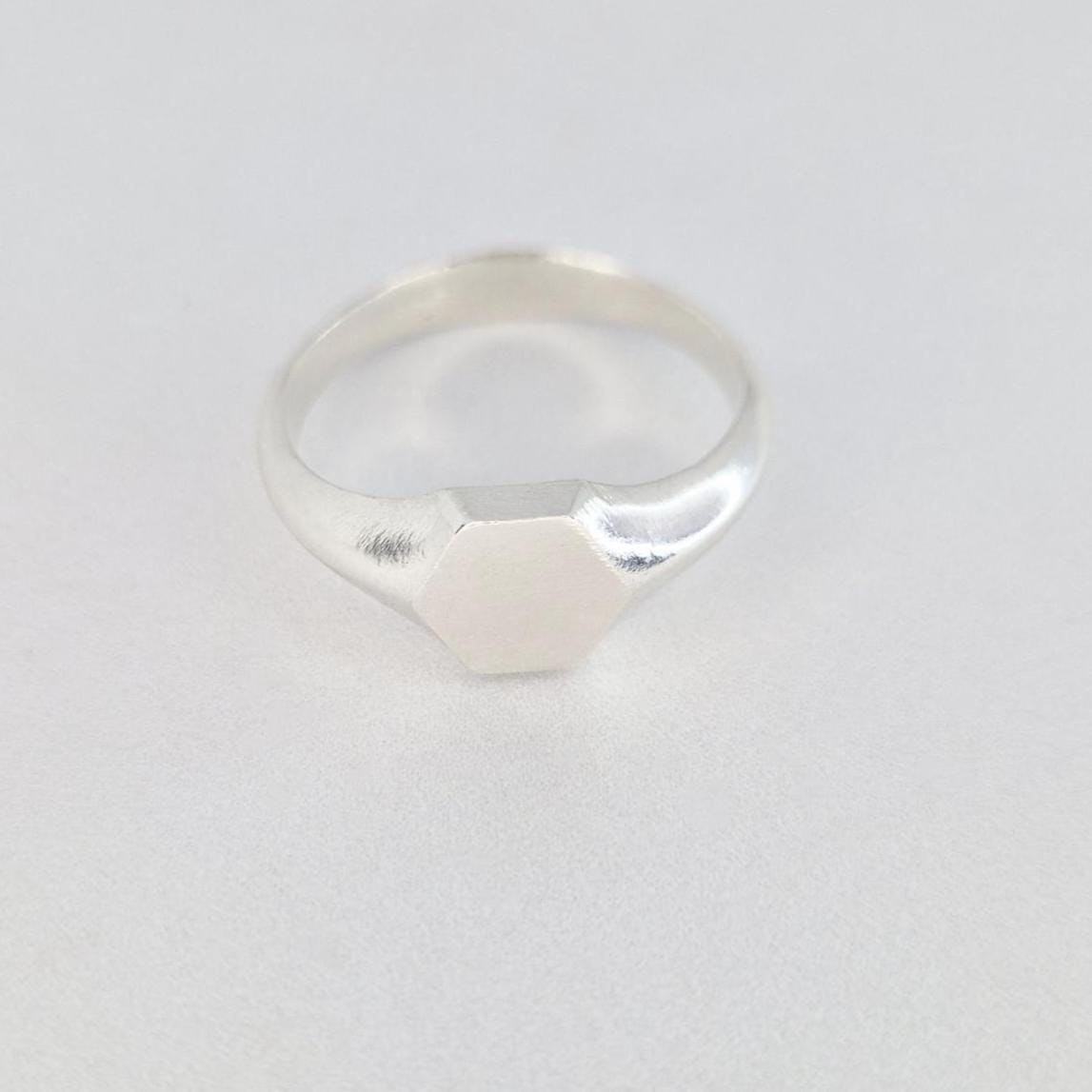 Sterling silver hexagon signet ring front view, clean geometric face with soft satin finish